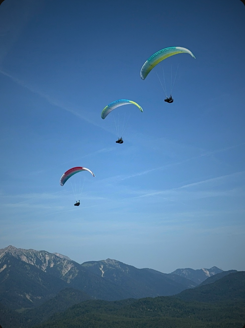 Paragliders flying above a mountain valley